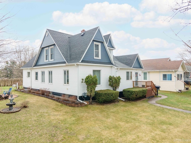 exterior space featuring roof with shingles, a deck, a front lawn, and a chimney