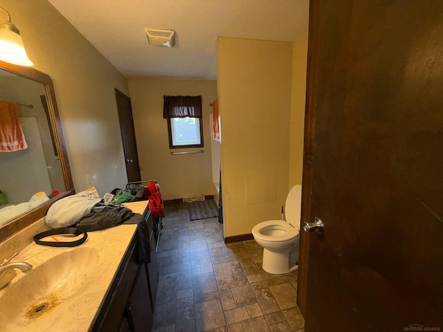bathroom with toilet, vanity, and visible vents