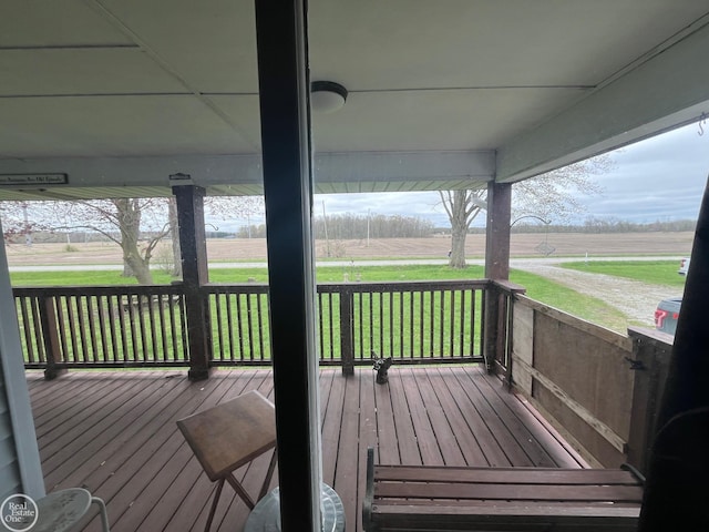 wooden terrace featuring a lawn and a rural view