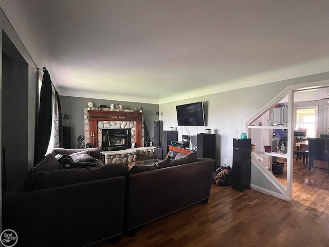 living area with a stone fireplace and dark wood finished floors