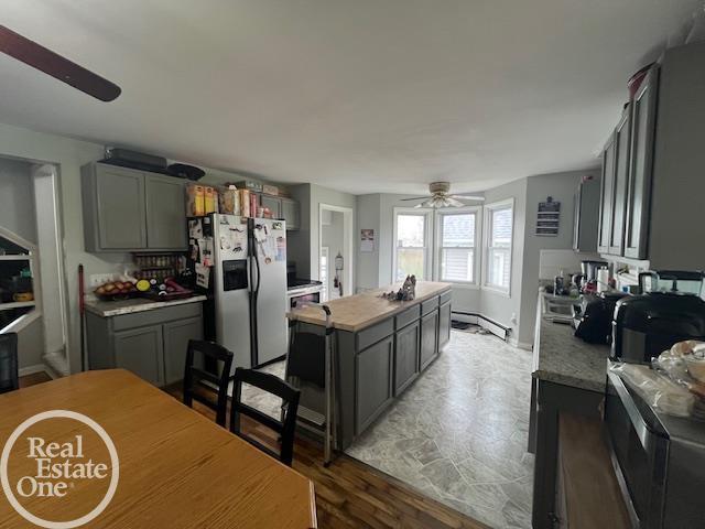 kitchen with a kitchen island, gray cabinetry, stainless steel fridge, and a ceiling fan