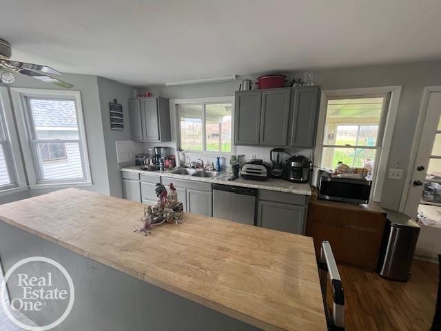 kitchen with light countertops, stainless steel appliances, gray cabinetry, and a sink