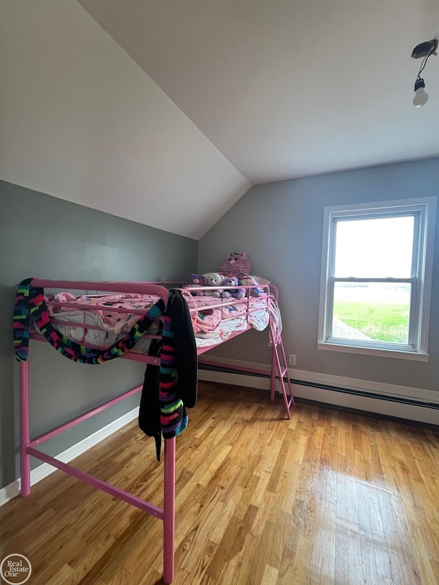 bedroom with a baseboard radiator, baseboards, wood finished floors, and lofted ceiling