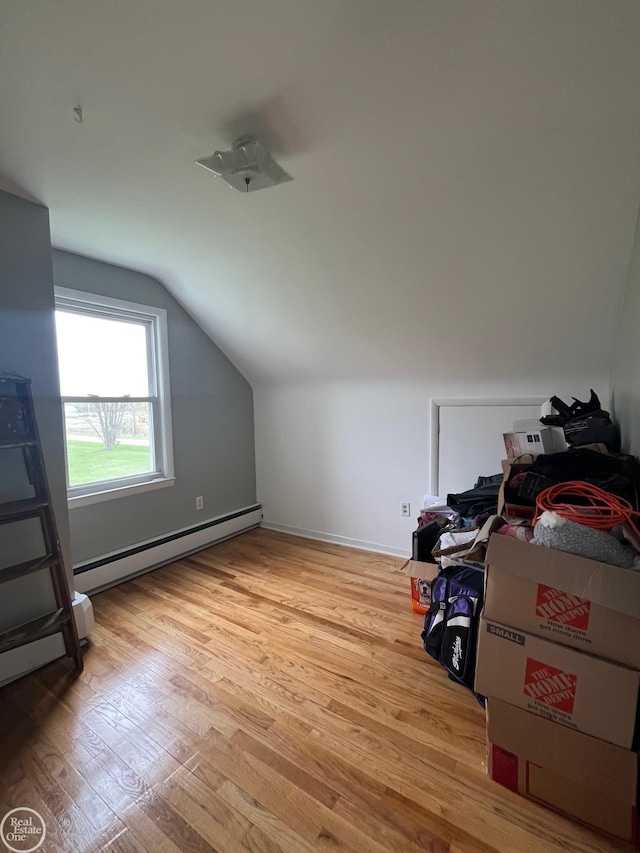 bonus room with a baseboard heating unit, lofted ceiling, and light wood-style flooring