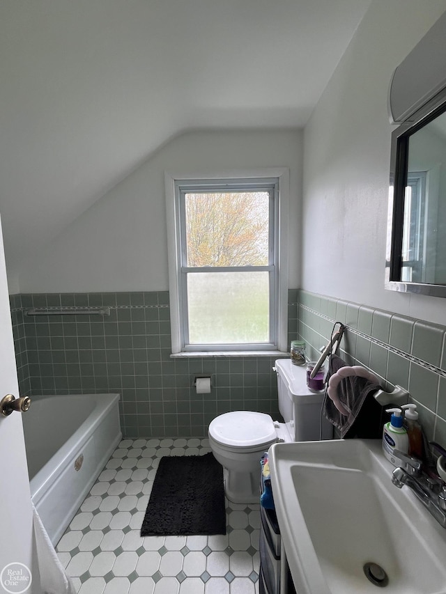 bathroom with tile walls, toilet, a tub to relax in, a sink, and vaulted ceiling