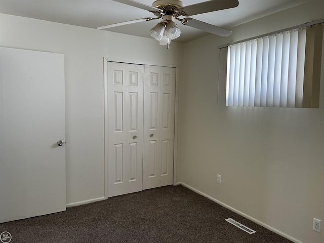 unfurnished bedroom featuring ceiling fan, a closet, dark colored carpet, and visible vents