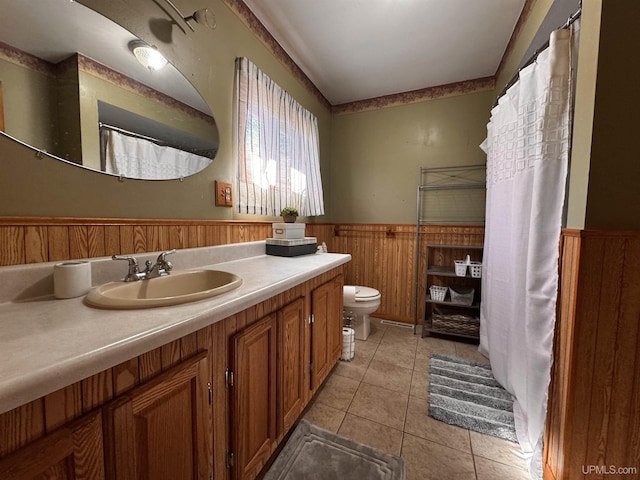 full bath with toilet, wainscoting, wooden walls, tile patterned floors, and vanity