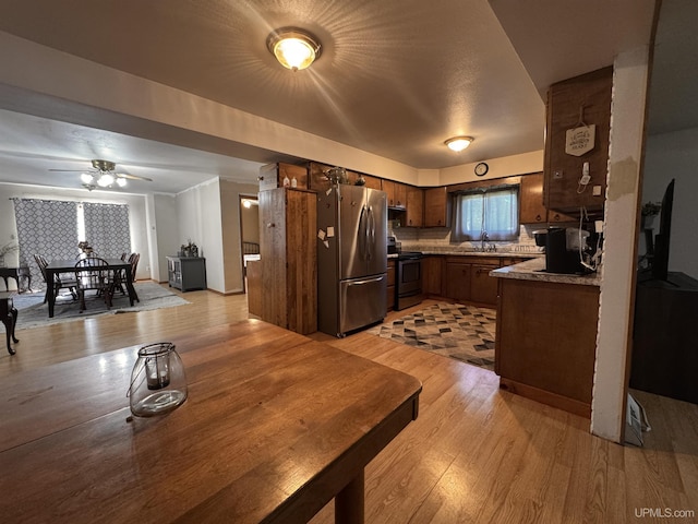 kitchen with a sink, ceiling fan, light wood-type flooring, and appliances with stainless steel finishes