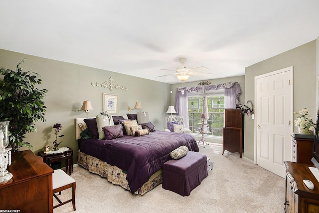 bedroom featuring light colored carpet, baseboards, and a ceiling fan