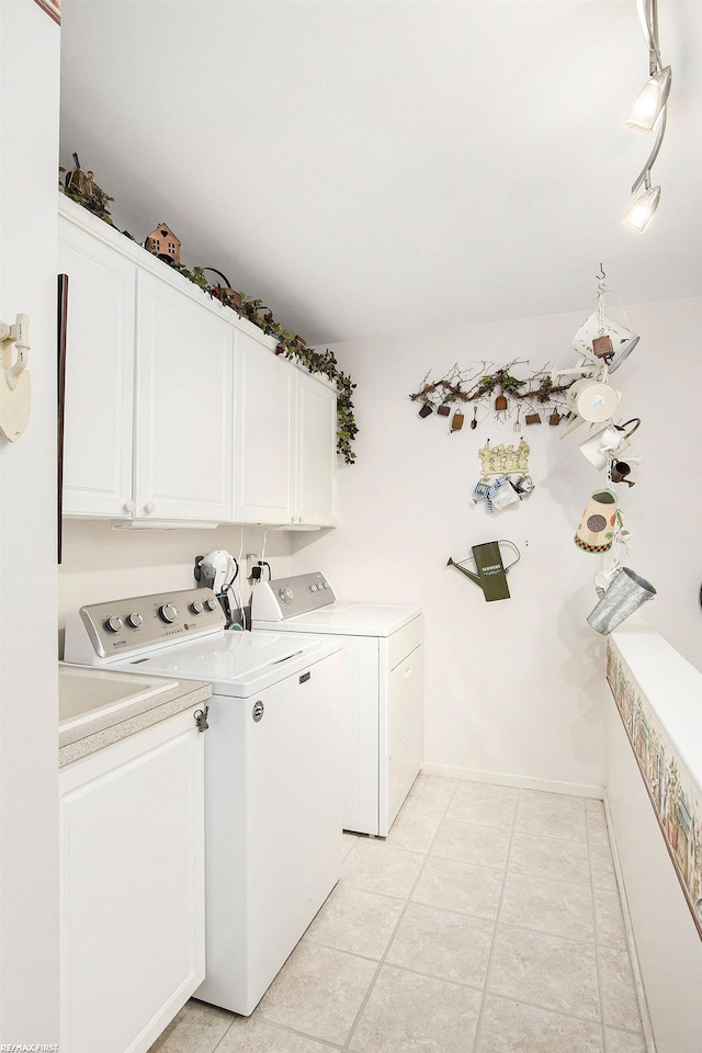 clothes washing area featuring baseboards, washer and dryer, light tile patterned flooring, and cabinet space