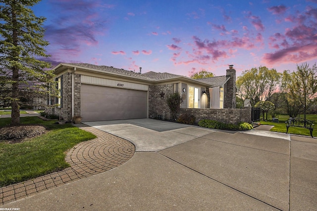 single story home featuring a chimney, driveway, a yard, brick siding, and an attached garage