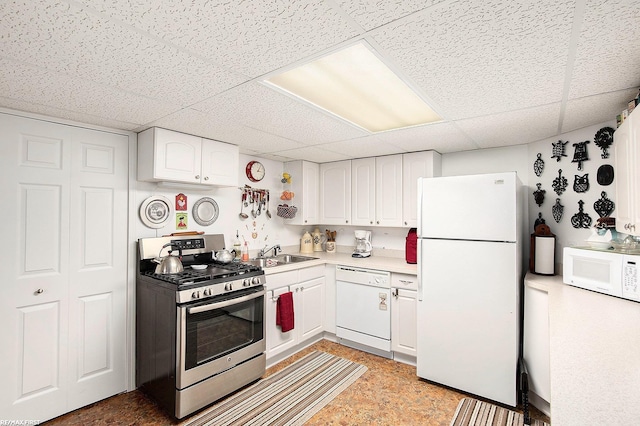 kitchen with a sink, white appliances, light countertops, white cabinets, and a paneled ceiling