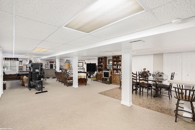 finished below grade area featuring a paneled ceiling, carpet, and visible vents