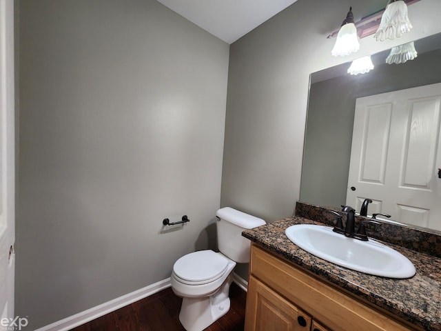 bathroom with vanity, toilet, baseboards, and wood finished floors