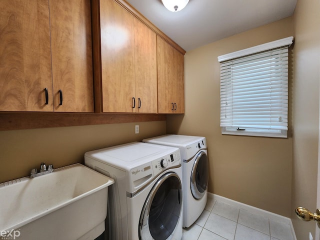 washroom featuring a sink, cabinet space, washing machine and clothes dryer, light tile patterned floors, and baseboards