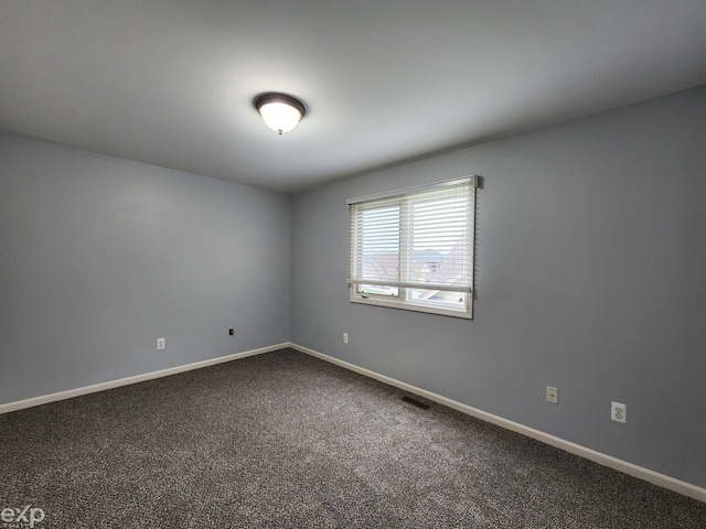 empty room with visible vents, baseboards, and dark colored carpet