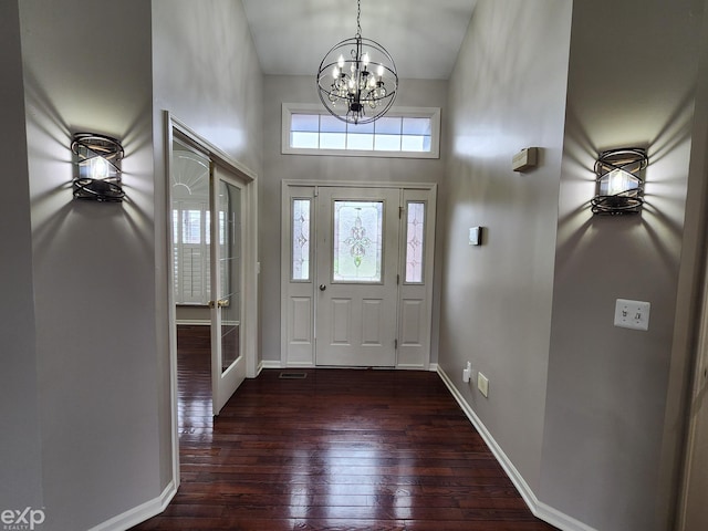 foyer with baseboards, a chandelier, dark wood-style floors, and a towering ceiling