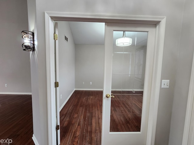 corridor with baseboards and wood finished floors