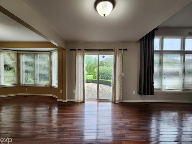 unfurnished room with baseboards, plenty of natural light, and hardwood / wood-style flooring
