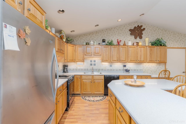 kitchen with a sink, black appliances, vaulted ceiling, light wood finished floors, and light countertops