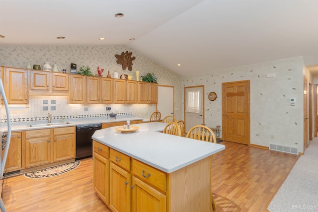 kitchen featuring light wood finished floors, dishwasher, visible vents, and a sink