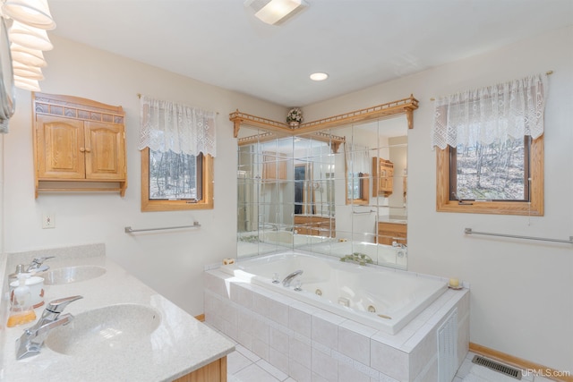 bathroom featuring a stall shower, a tub with jets, double vanity, and a sink