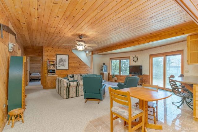 dining space featuring light colored carpet, wood walls, ceiling fan, and wood ceiling