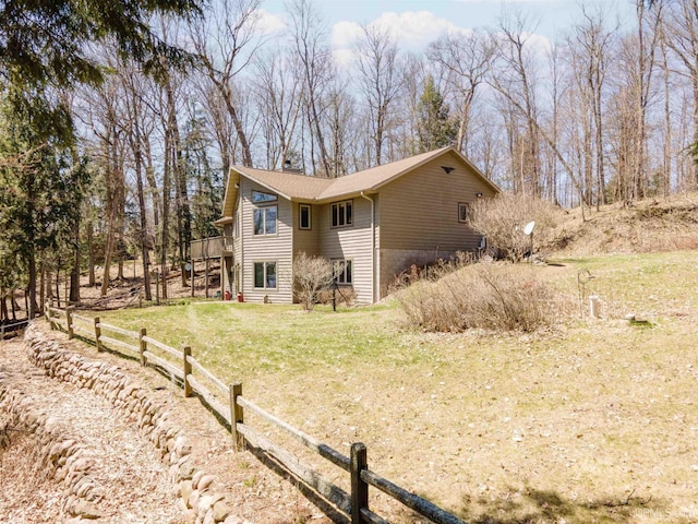 view of side of property with a yard, a deck, a chimney, and fence