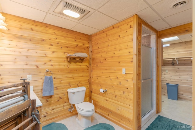 full bathroom featuring a drop ceiling, a stall shower, visible vents, and wooden walls
