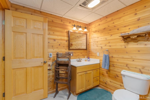 bathroom featuring toilet, a paneled ceiling, visible vents, wood walls, and vanity