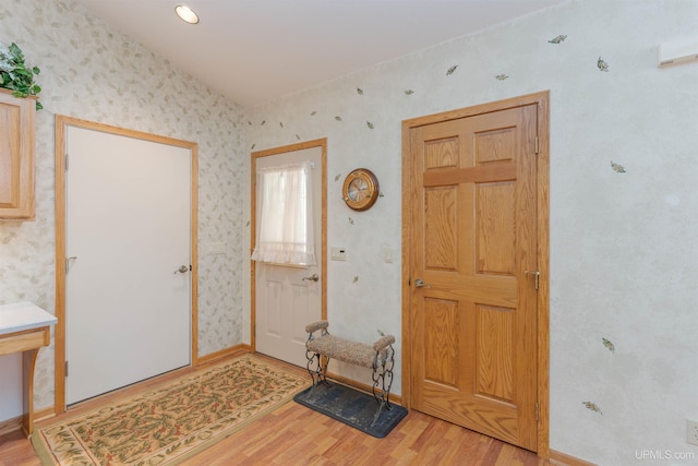 entrance foyer with wallpapered walls, light wood-style flooring, and baseboards