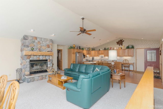 living room with wallpapered walls, light wood finished floors, ceiling fan, vaulted ceiling, and a fireplace