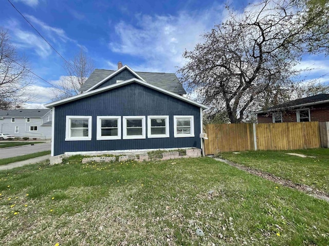 301 Michigan Ave, Bay City, MI 48708 - view of home's exterior featuring fence, a chimney, and a lawn