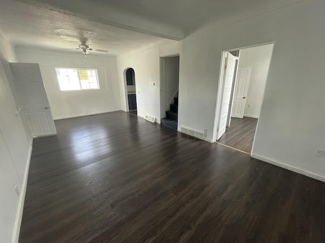 301 Michigan Ave, Bay City, MI 48708 - unfurnished living room featuring dark wood finished floors, visible vents, ceiling fan, arched walkways, and stairs