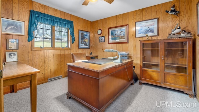 office with visible vents, wood walls, a ceiling fan, and light carpet