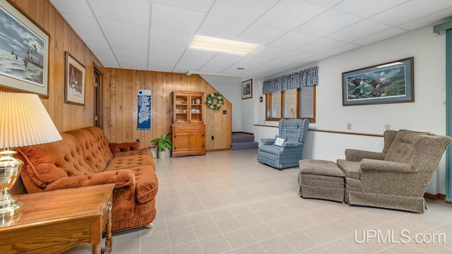 living room with a paneled ceiling and wooden walls