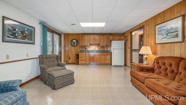 living area with baseboards and wood walls