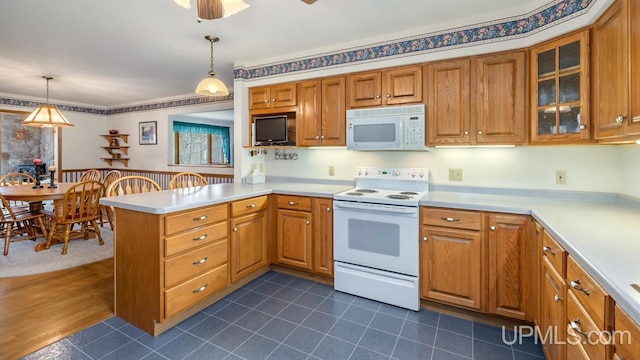 kitchen with a peninsula, white appliances, decorative light fixtures, light countertops, and glass insert cabinets