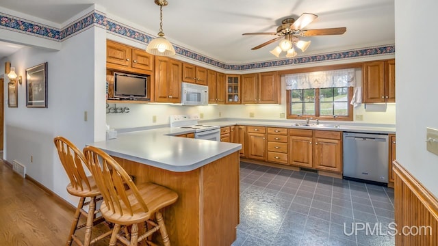 kitchen with white appliances, ceiling fan, a sink, a peninsula, and brown cabinets