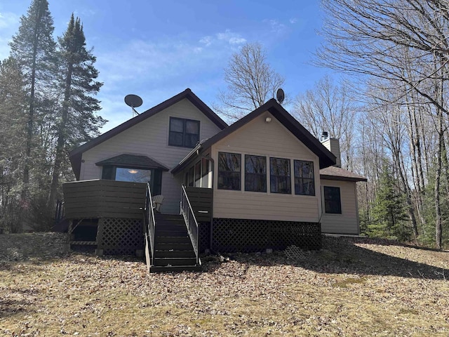 rear view of property featuring a chimney, a deck, and stairway