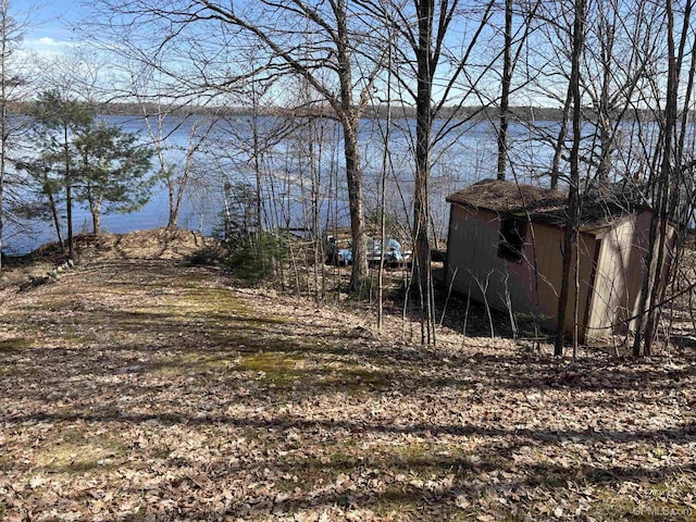 view of yard with a water view, an outbuilding, and a shed