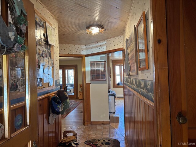 hall with wallpapered walls, a wainscoted wall, and a baseboard radiator