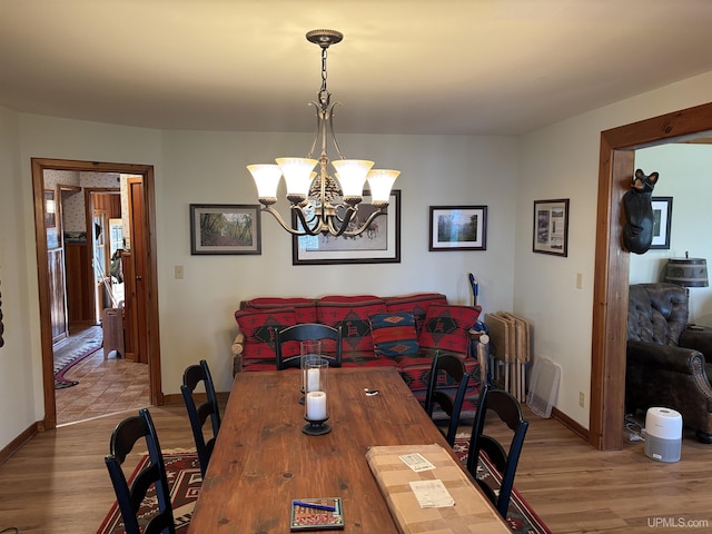 dining space with wood finished floors, a chandelier, and baseboards