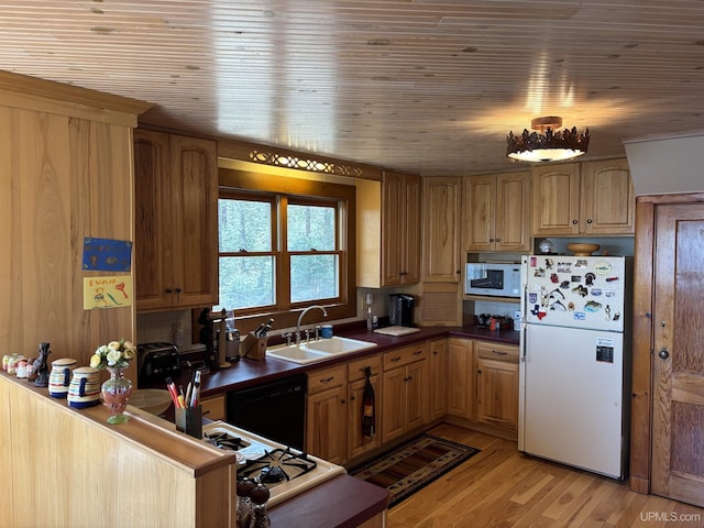 kitchen with white appliances, a sink, light wood-style floors, wood ceiling, and dark countertops