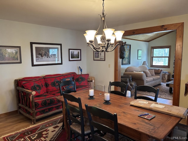 dining space with a chandelier, wood finished floors, lofted ceiling, and baseboards