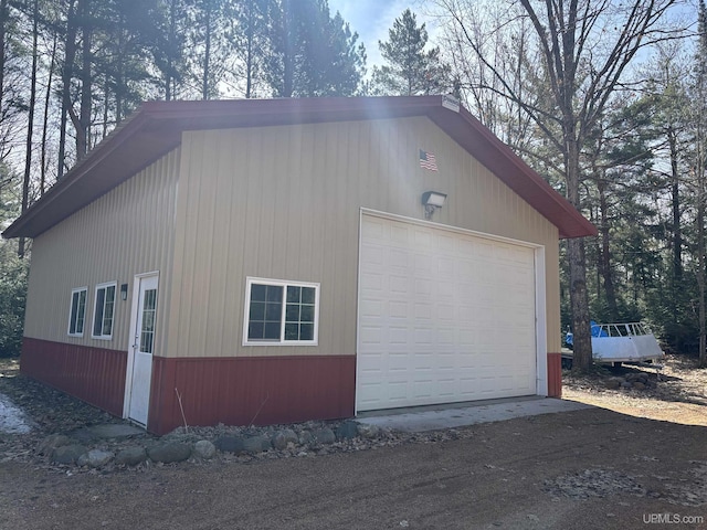 view of home's exterior with dirt driveway, an outbuilding, and a detached garage