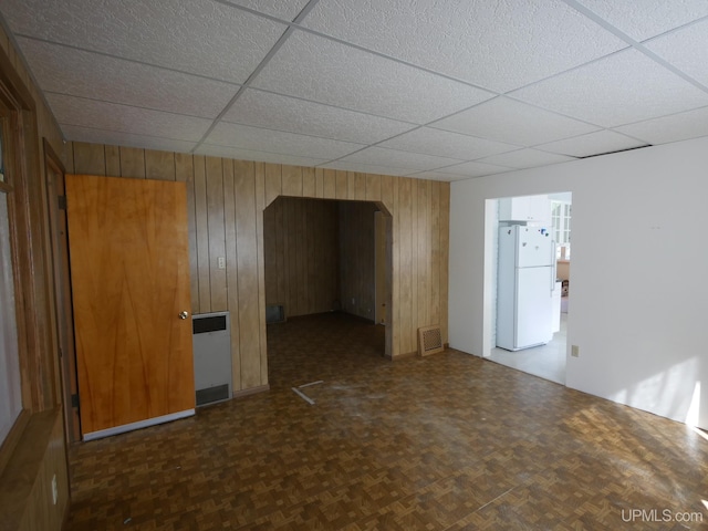 unfurnished room featuring a drop ceiling, visible vents, and wood walls