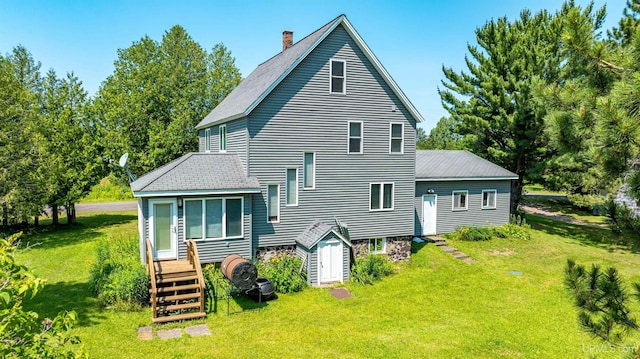 rear view of property with a yard, a chimney, and a shingled roof