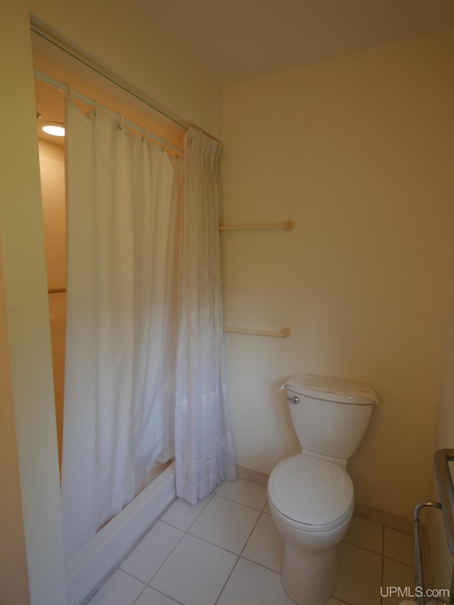 full bathroom with shower / bath combo, toilet, baseboards, and tile patterned floors