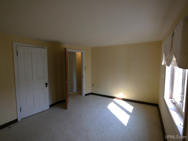 unfurnished room with light carpet and baseboards